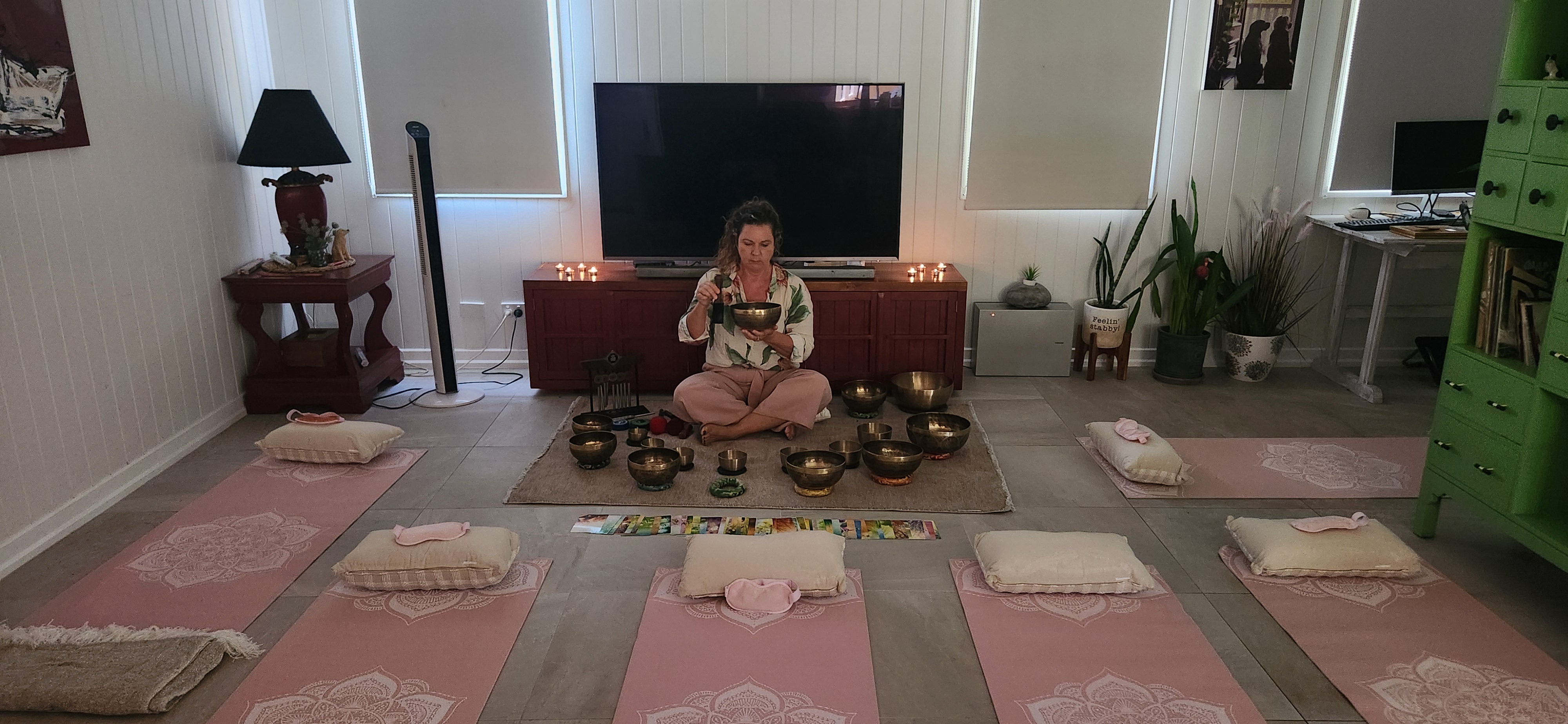 Sound healing facilitator playing singing bowls during a session